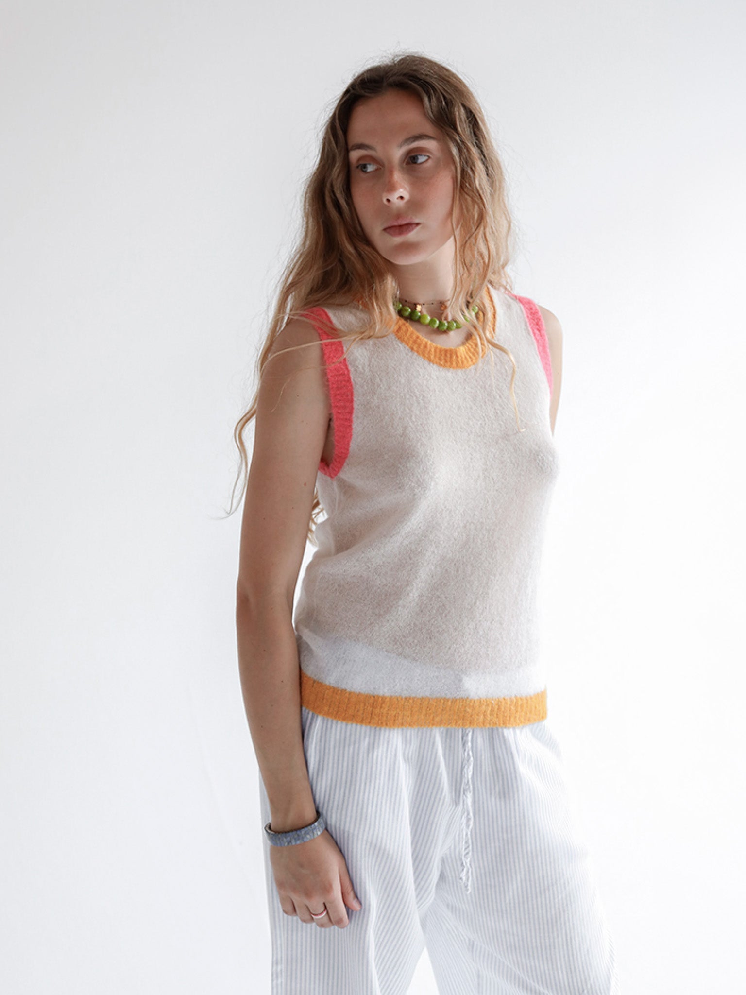 Woman wearing a sleeveless top with colorful straps against a white background