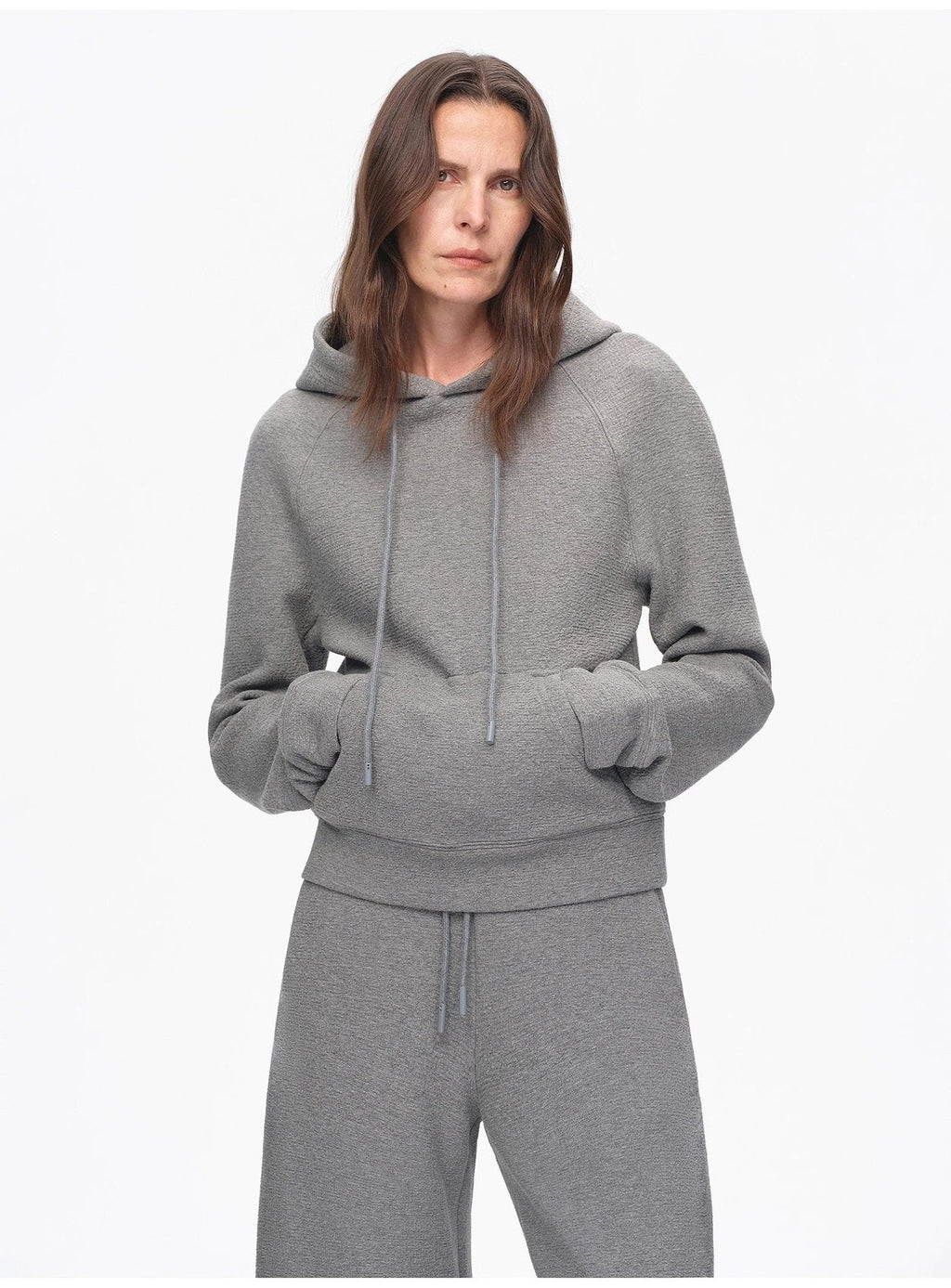 Person wearing a gray hoodie and pants on a white background