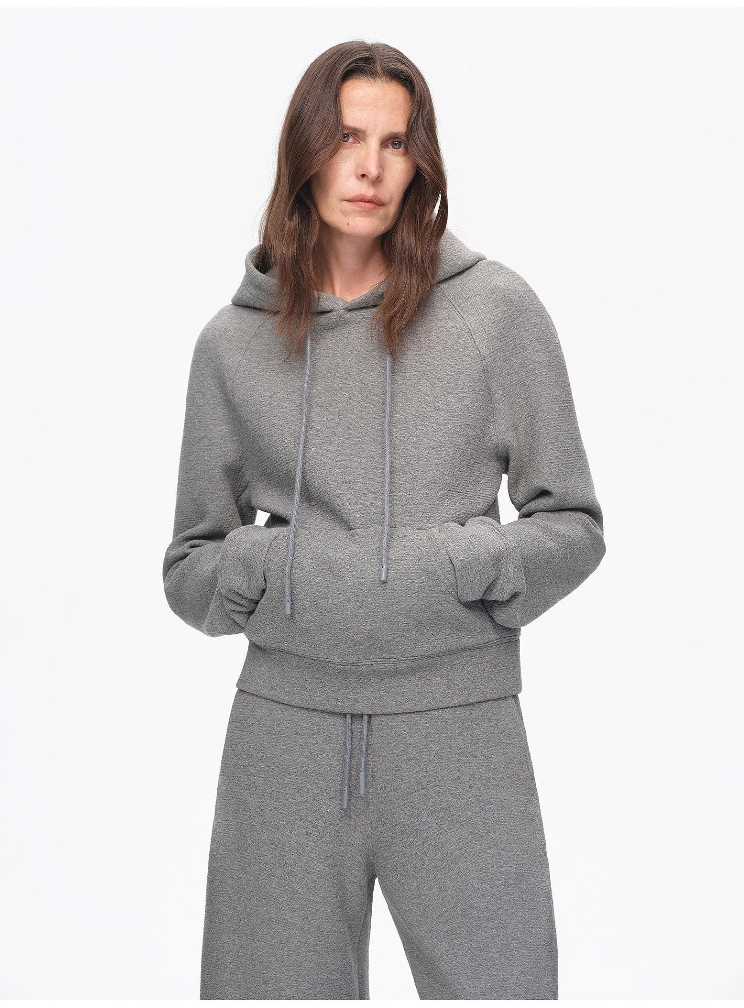 Person wearing a gray hoodie and pants on a white background