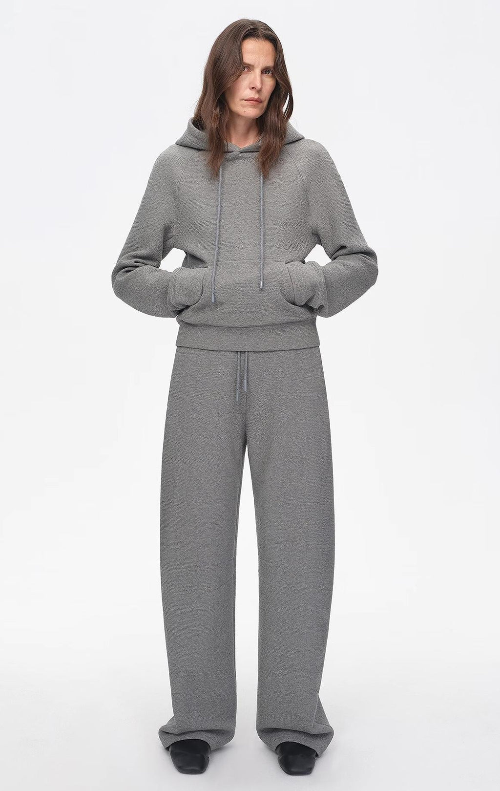 Person wearing a gray tracksuit on a white background