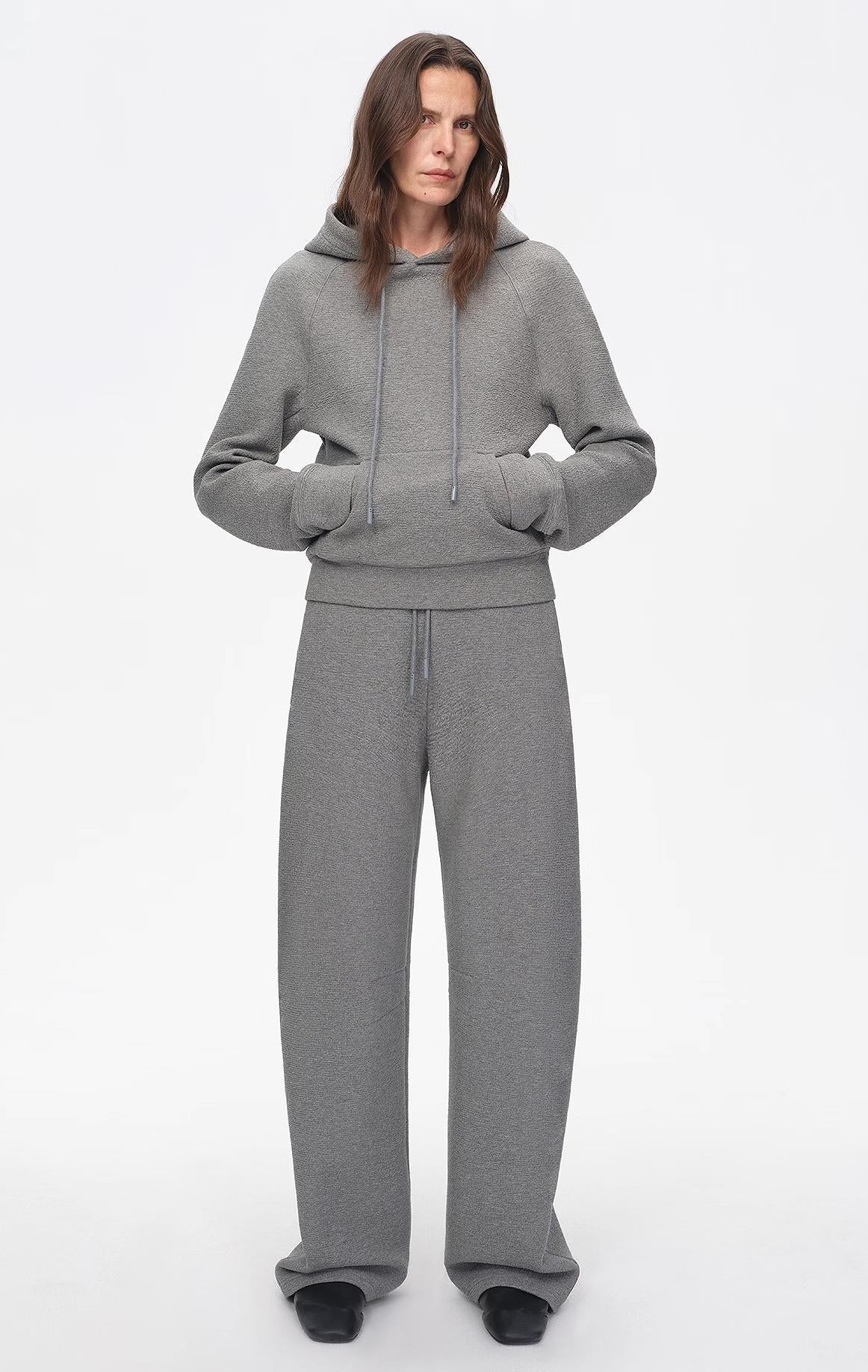 Person wearing a gray tracksuit on a white background