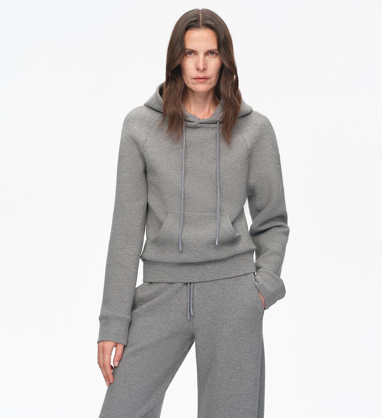 Woman wearing a gray hoodie and pants on a white background
