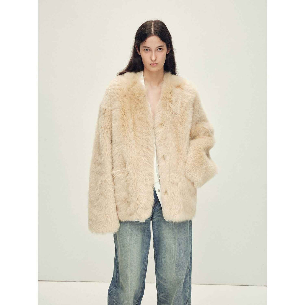Person wearing a cream fur coat and jeans on a white background