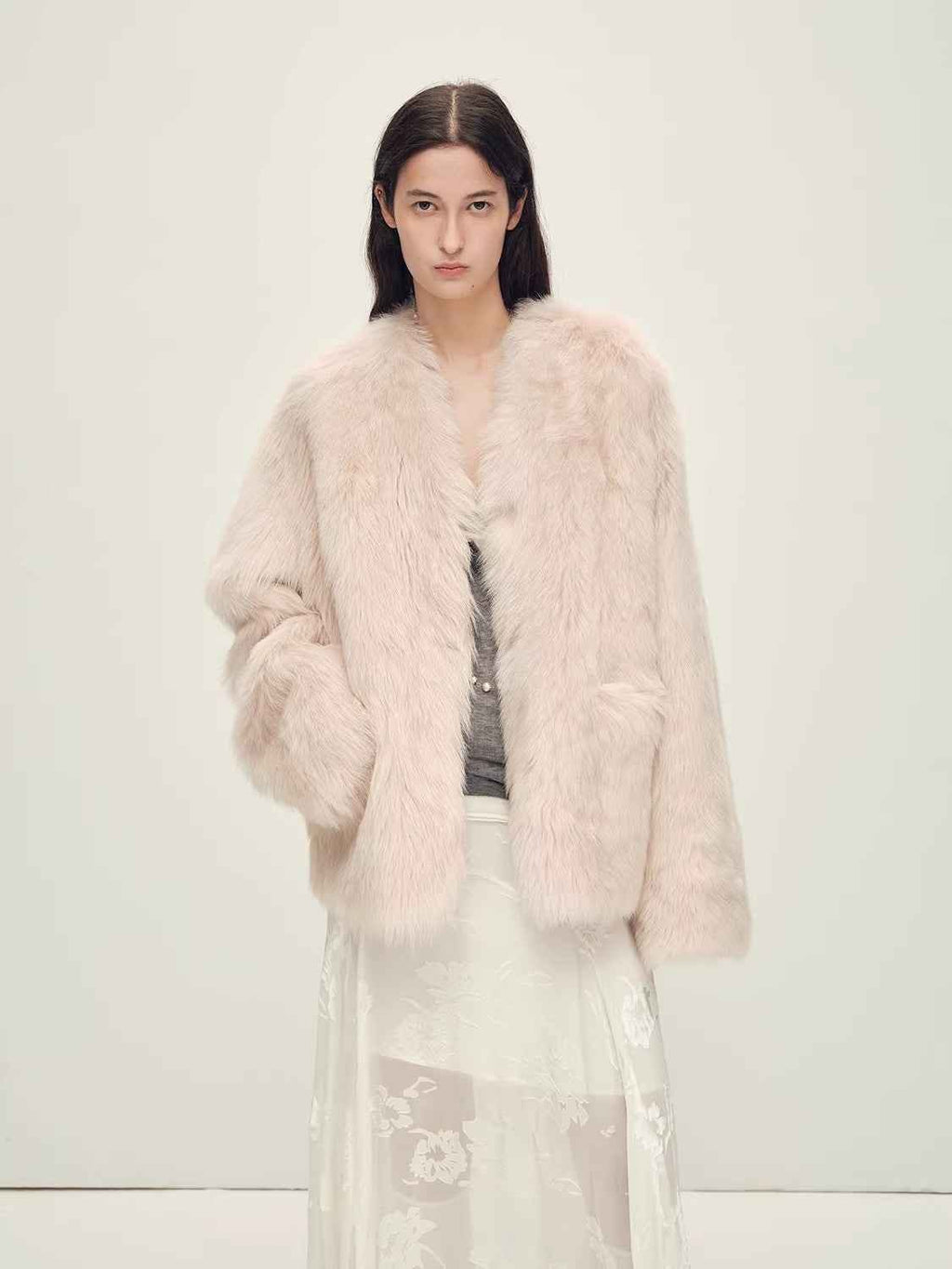 Woman wearing a light pink fur coat against a white background