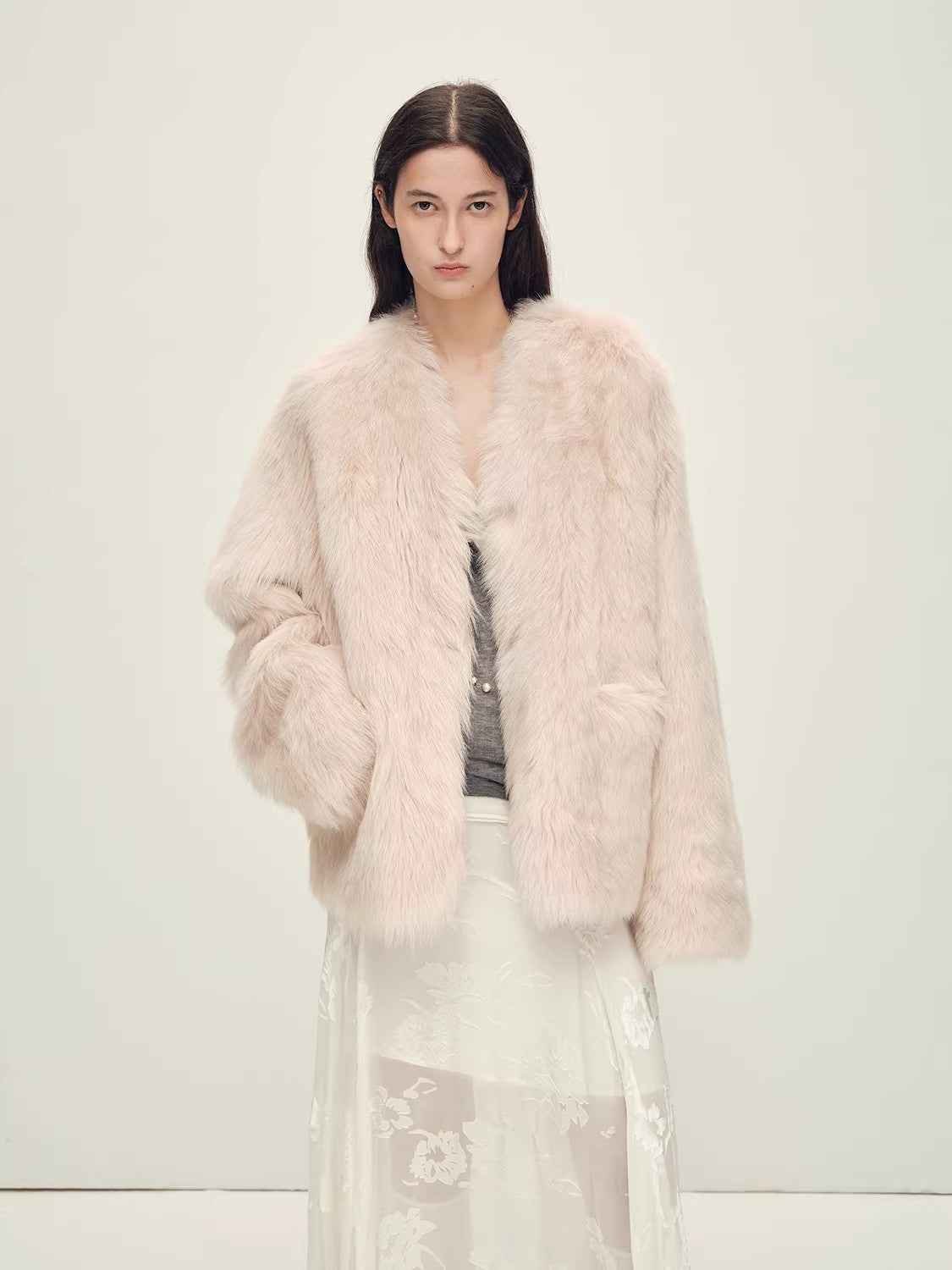 Woman wearing a light pink fur coat against a white background