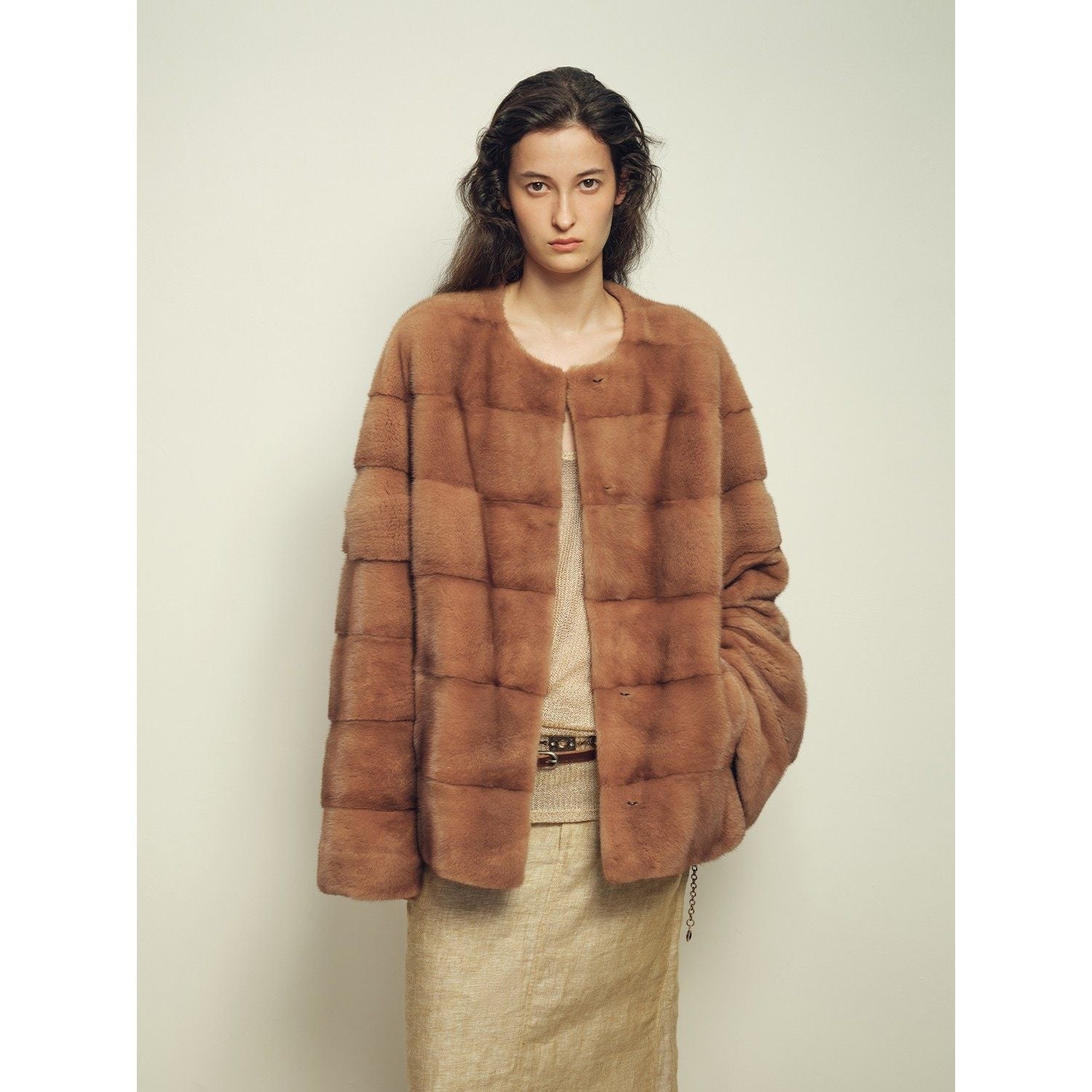 Woman wearing a brown fur coat against a plain background