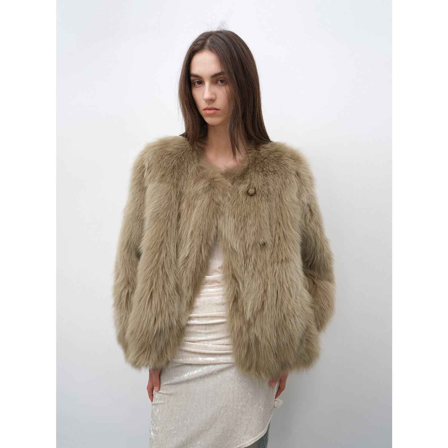 Woman wearing a fluffy beige jacket against a white background