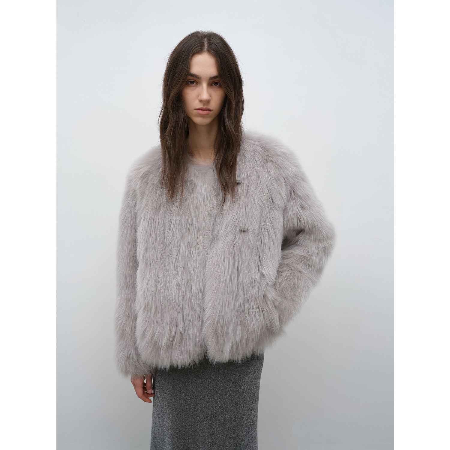 Person wearing a fluffy gray jacket against a plain background