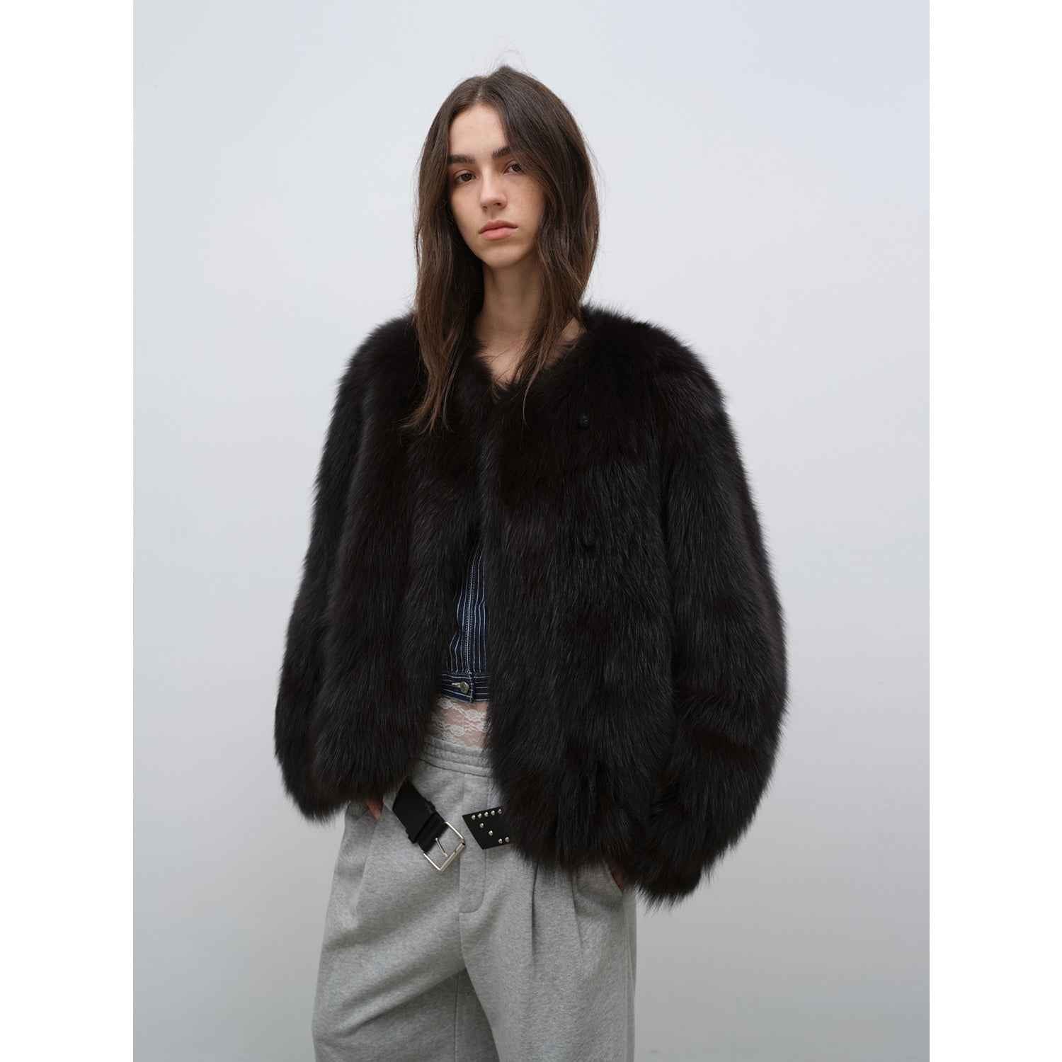 Person wearing a black fur coat against a plain background