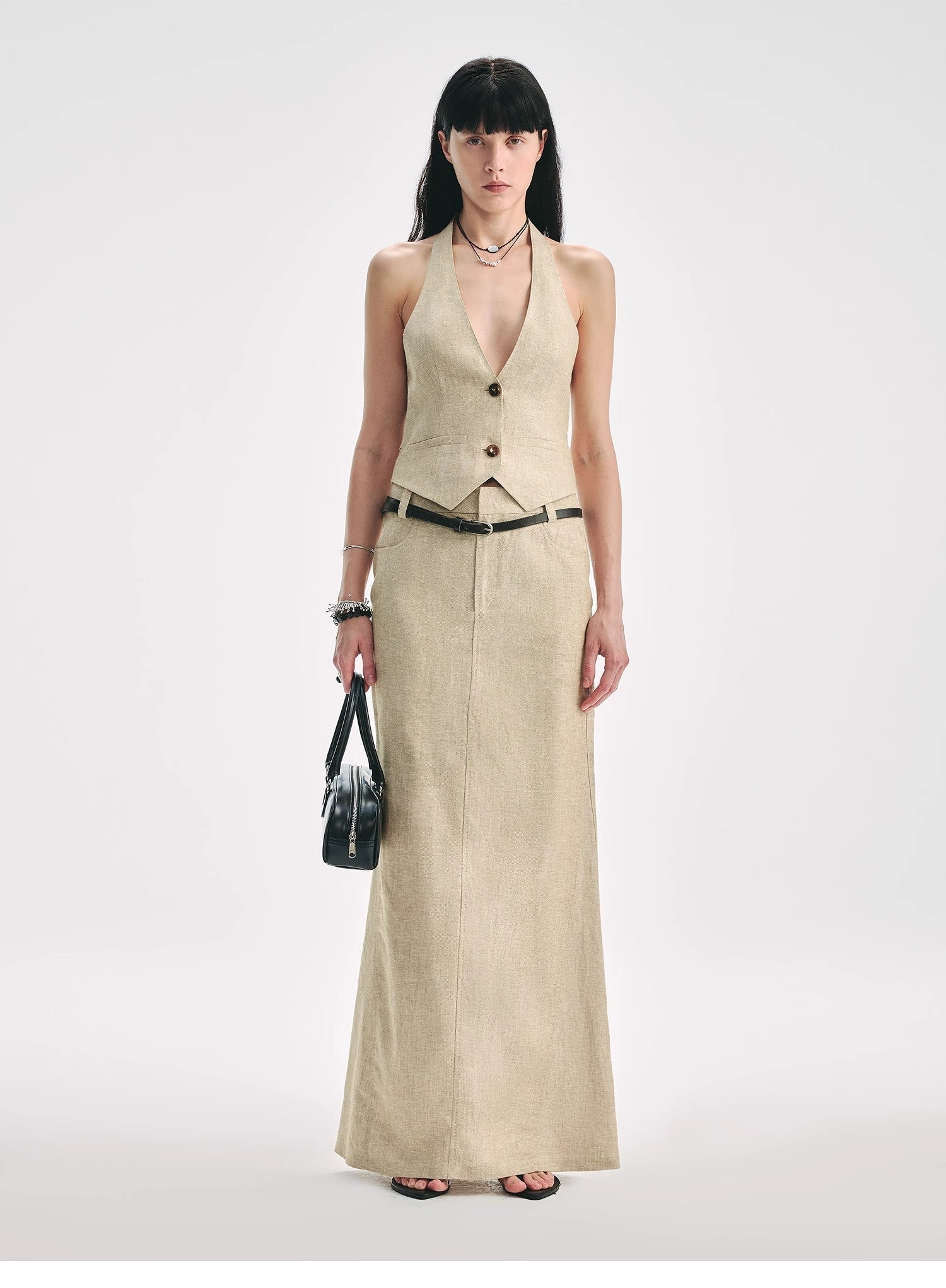 Woman wearing a beige sleeveless dress with buttons on a white background