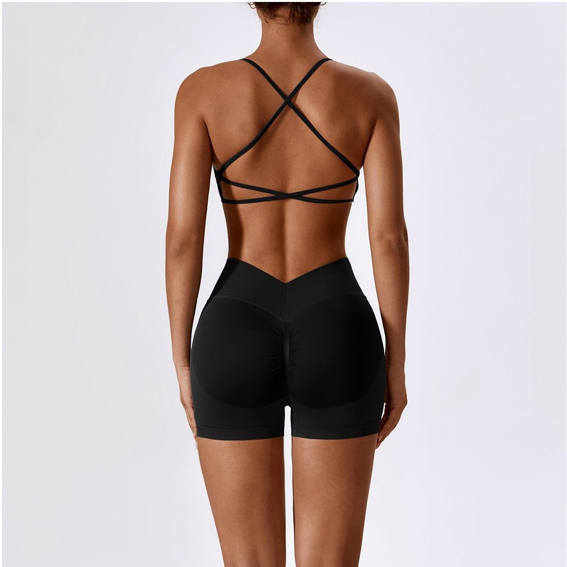 Person wearing a black strappy top and shorts on a white background