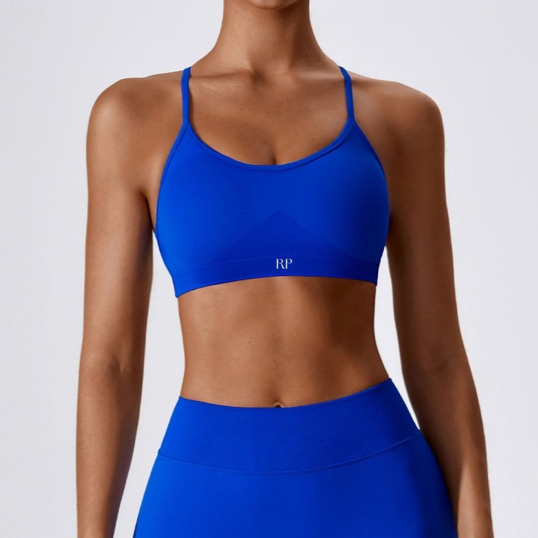 Person wearing a blue sports bra and leggings with a brand logo on a white background