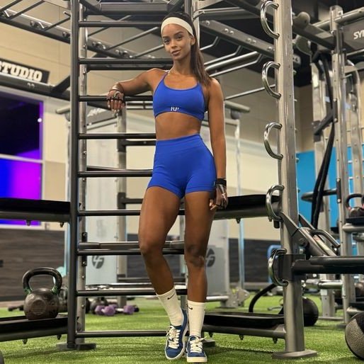 Woman in blue athletic wear posing in a gym setting