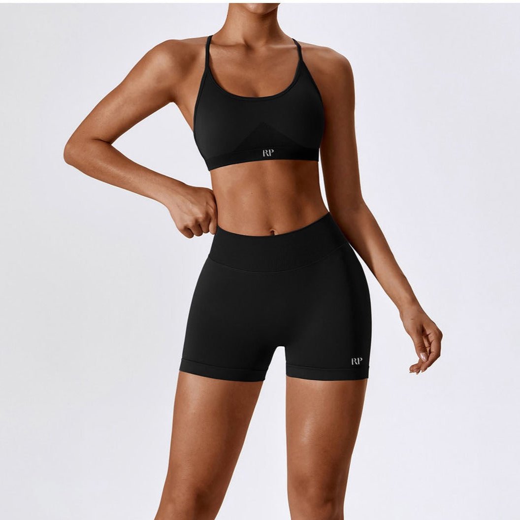Person wearing a black sports bra and shorts set on a white background