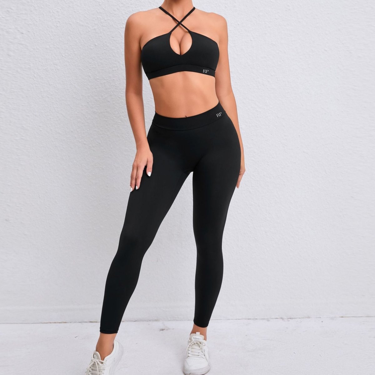 Person wearing a black sports bra and leggings set on a light gray background