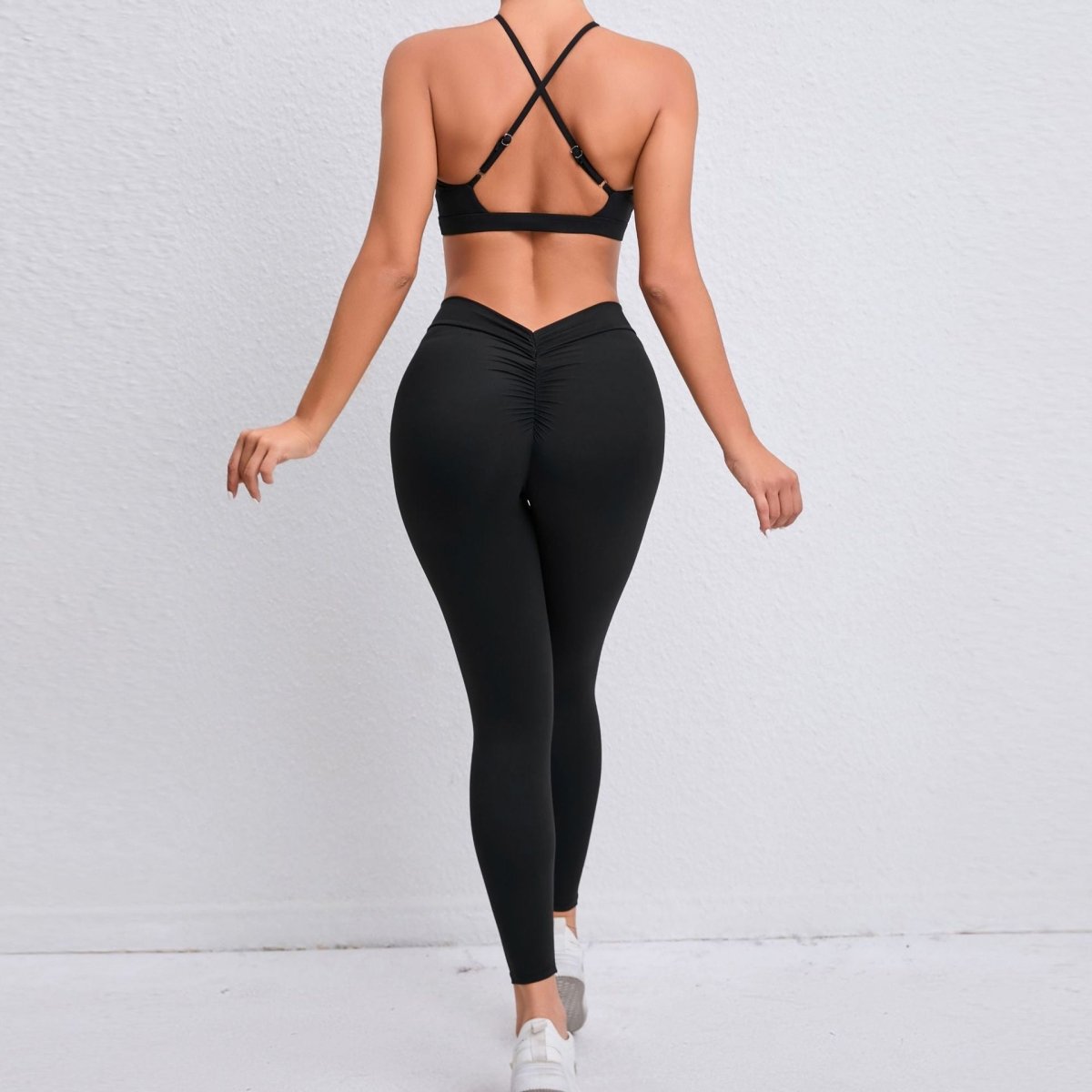Person wearing a black sports bra and leggings on a light gray background