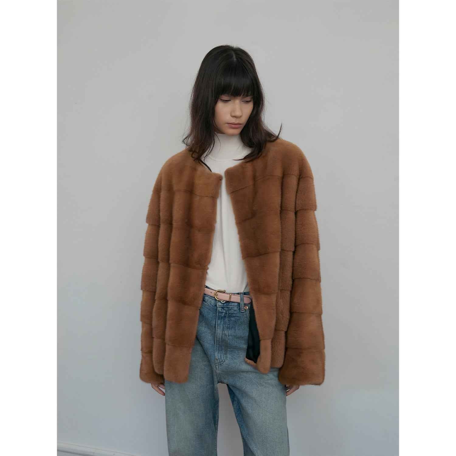 Person wearing a brown fur coat against a plain background